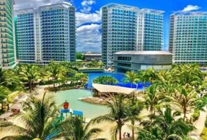 A high-rise hotel with multiple floors, a central pool area, and surrounding palm trees.