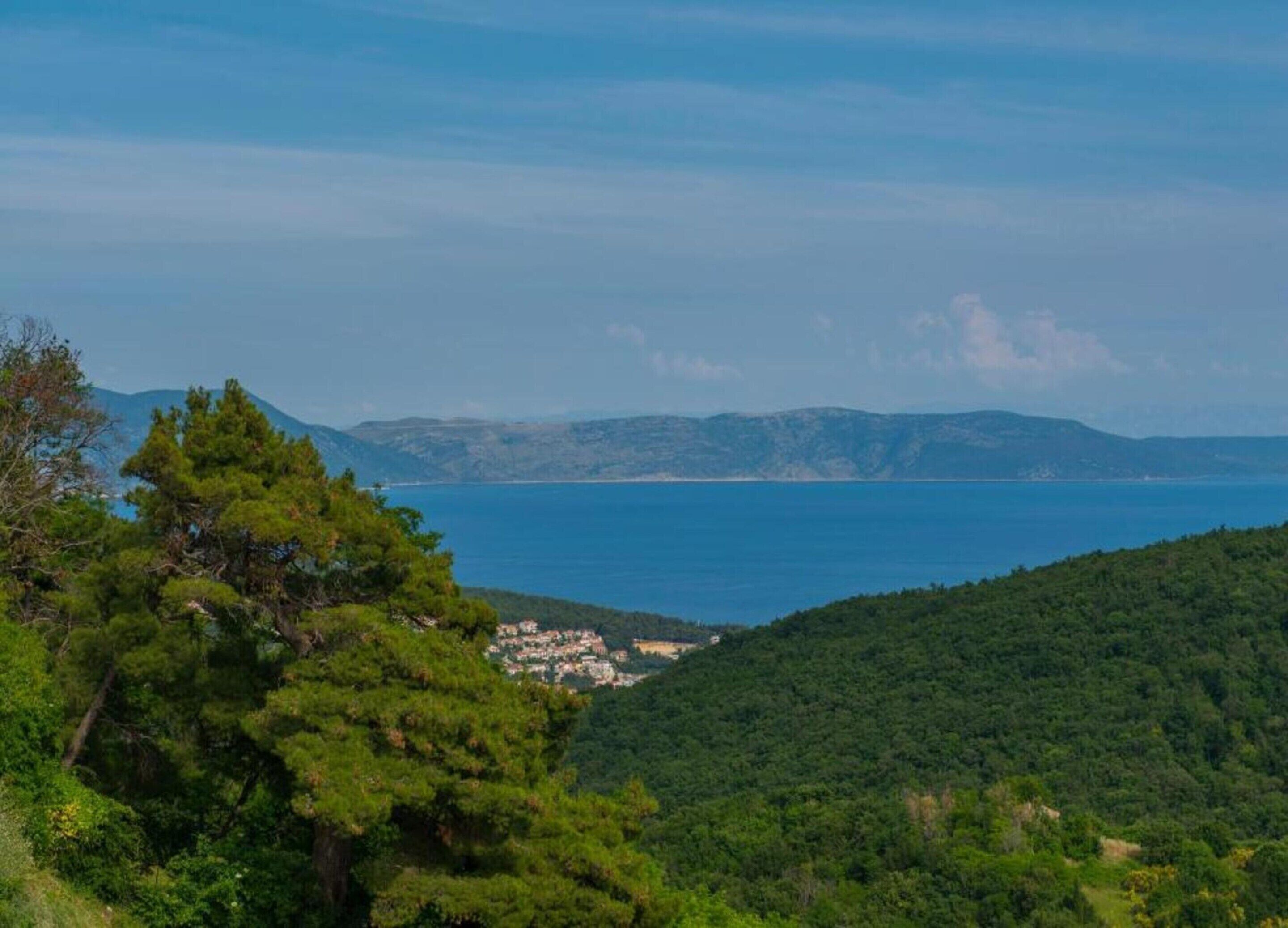 Paisagem costeira com vegetação densa e vista para o mar.