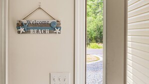 Een houten bord met de tekst 'Welcome to the BEACH' en zeester decoraties.