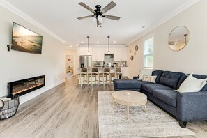 A modern living room with a fireplace, a sectional sofa, a coffee table, and a TV mounted on the wall. - Mid Term Home in Southport, just mins from DT Southport and Oak Island Beaches (Southport)
