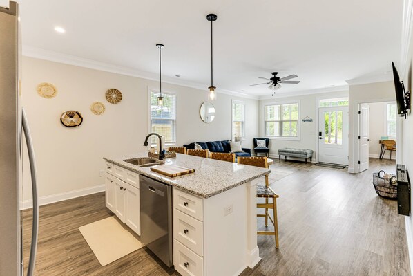 A spacious kitchen with a central island, wooden flooring, and a ceiling fan.