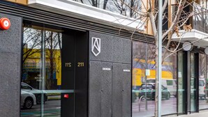 Een modern gebouw met een glazen ingang, een brandmeldpaneel en een logo.