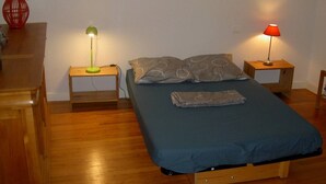 A small, neatly arranged bedroom with a single bed, two bedside tables, and a wall-mounted painting.