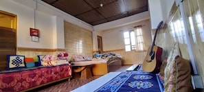 A room with two beds, a guitar, and a window with curtains. - Buddha Home Stay Kaza (Kaza)