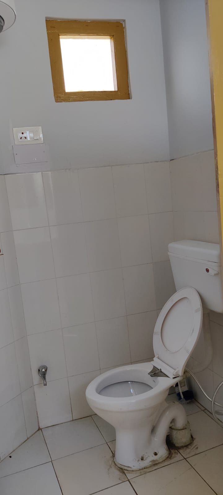 Un bagno piccolo con un WC bianco, una finestra e pareti piastrellate.