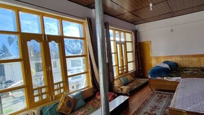 A room with large windows, a wooden ceiling, and a bed with pillows and a blanket. - Buddha Home Stay Kaza (Kaza)
