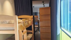 A bunk bed room with a wooden headboard, a built-in shelf, and a window with blinds.