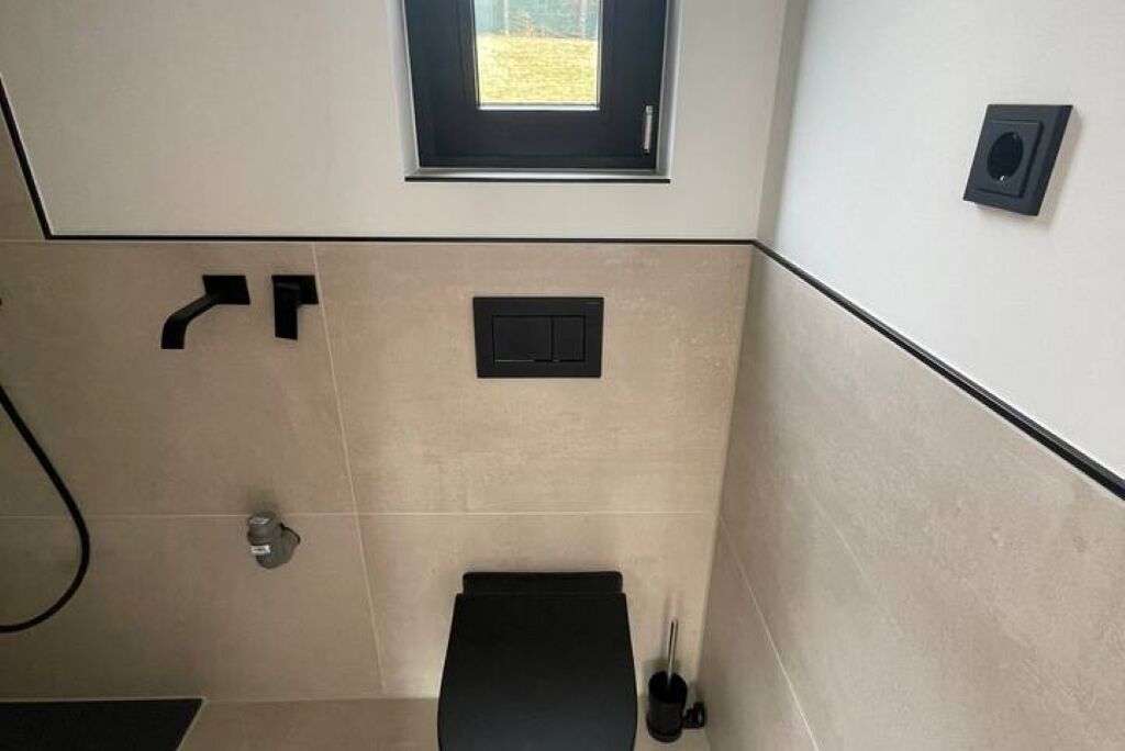 Ein Badezimmer mit Toilette, Dusche und Fenster.