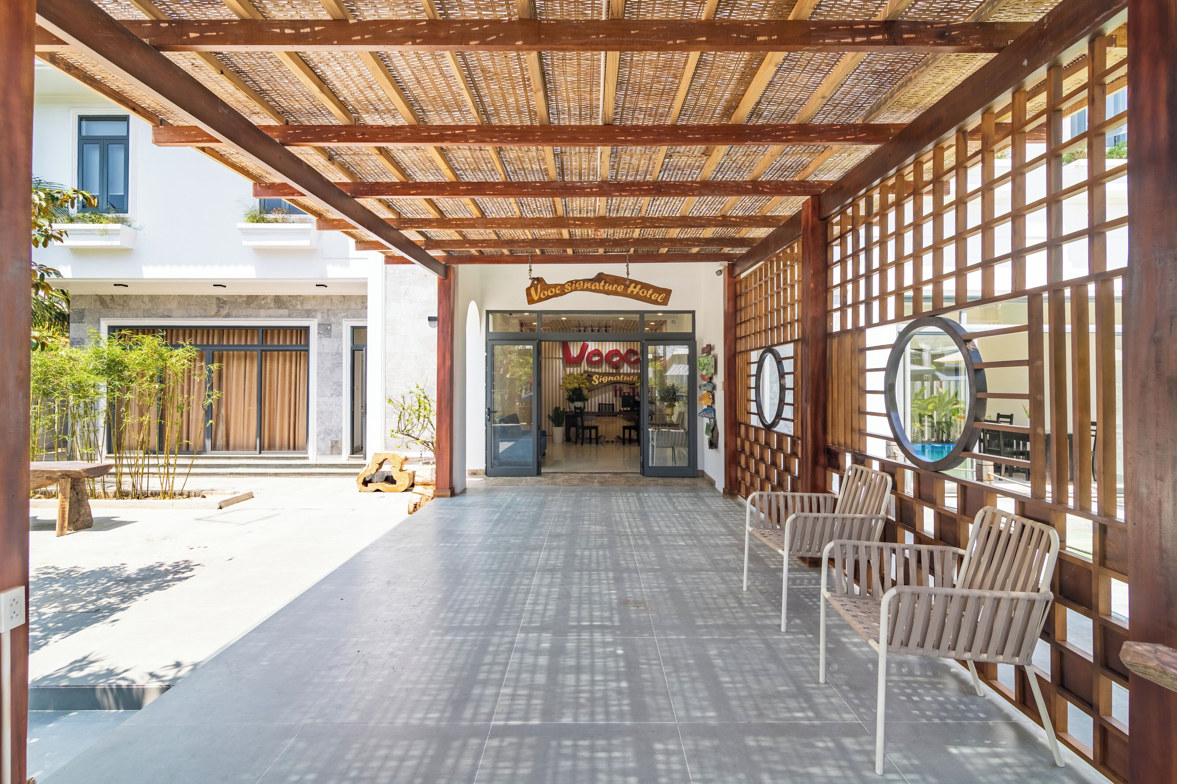 A hotel entrance with a covered walkway, seating area, and a sign for the "VooC Signature Hotel".