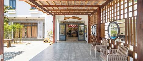 A hotel entrance with a covered walkway, seating area, and a sign for the "VooC Signature Hotel".