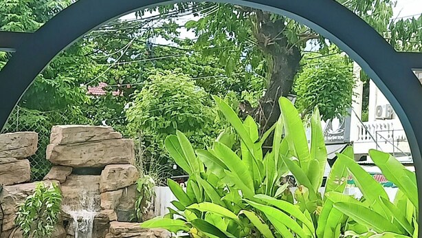 A swimming pool with a waterfall feature and lush greenery. - Vooc Signature Hotel Hoi An (Da Nang)