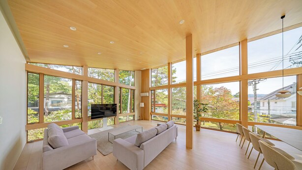 Un salón amplio con ventanas grandes, un televisor de pantalla plana y una zona de comedor con sillas.