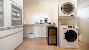 Una sala de lavandería con lavadora, secadora y un estante con utensilios de cocina.