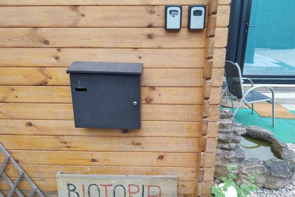 Un muro in legno con un quadro elettrico nero, due dispositivi fissati al muro e un cartello con scritto "BIOTOPIA".