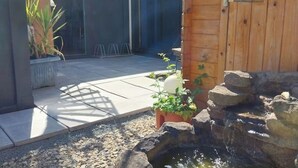 Un espace patio agrémenté d’un petit élément décoratif aquatique, de plantes en pot et d’une clôture en bois.
