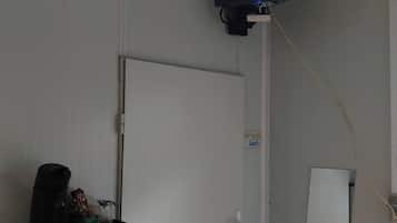 Une pièce avec un téléviseur fixé au mur, une porte et un tableau blanc.