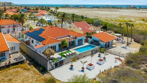 Zona residencial con casas, piscina y playa al fondo.
