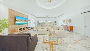 Una sala de estar moderna con un televisor grande, un sofá modular, una mesa de centro y un piso de mármol.