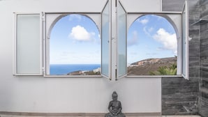 Ein Zimmer mit Buddha-Statue, Meerblick und modernem architektonischen Design.