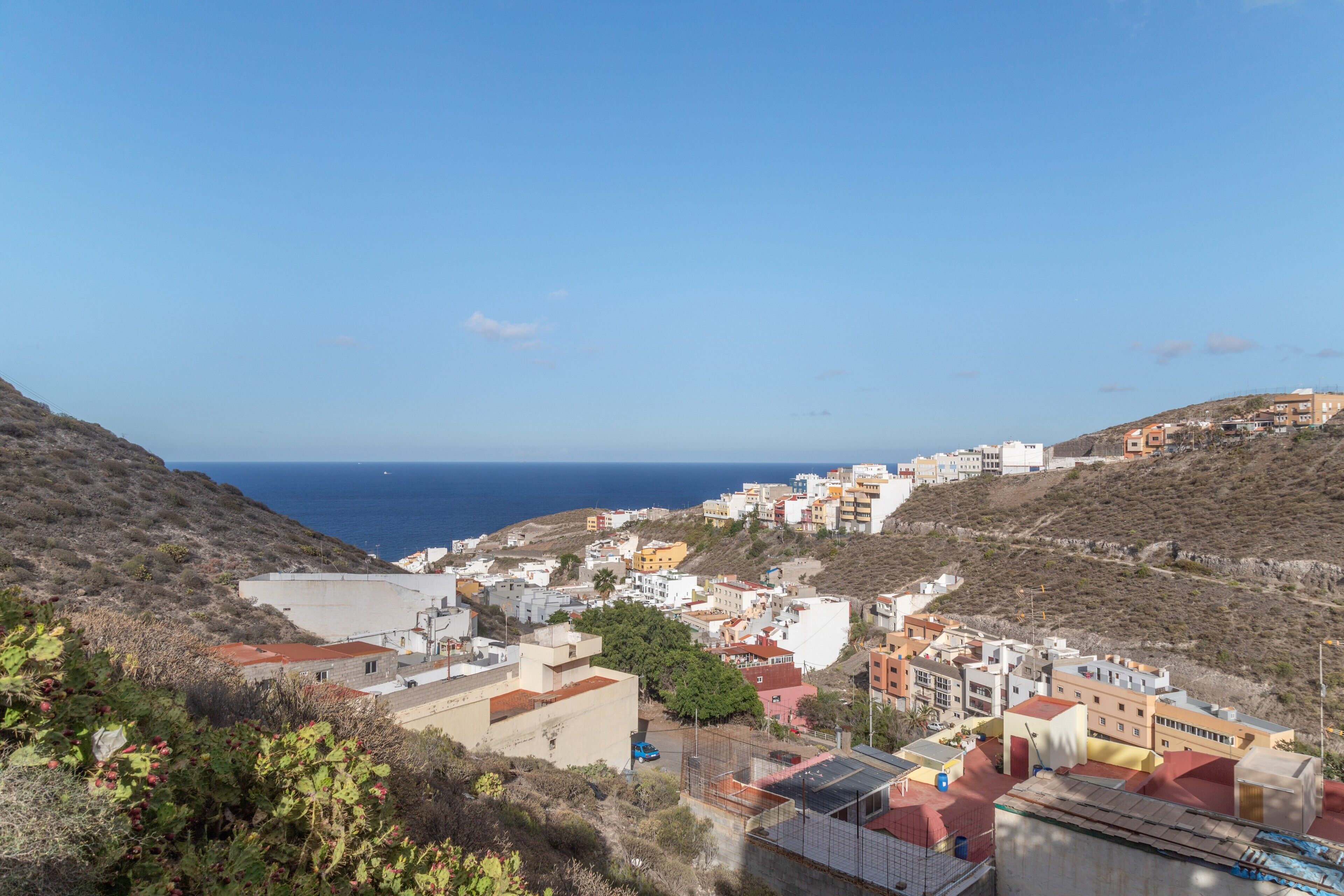 Une ville côtière avec des bâtiments, un ciel dégagé et la mer en arrière-plan.