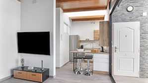 Eine moderne Küche mit großem Fernseher, Holzboden und einer Steinwand.