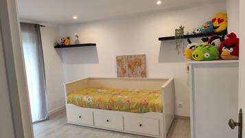 Une chambre avec un lit, une commode, une étagère remplie de peluches et une carte du monde accrochée au mur.