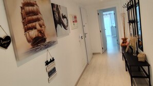 En hall med en stor målning av ett skepp, en hjärtformad skylt och en svart bänk med en vas.