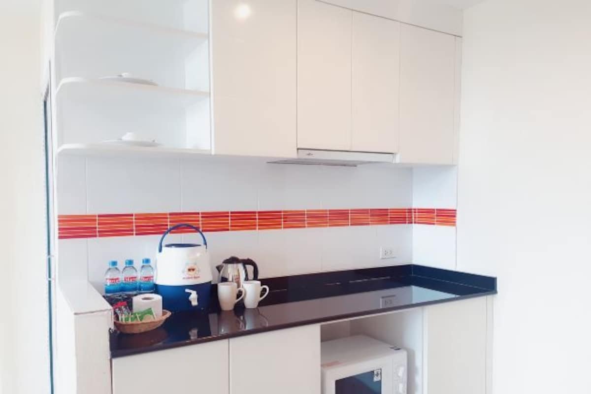 A modern kitchen with white cabinets, a black countertop, and a red and white tiled backsplash.