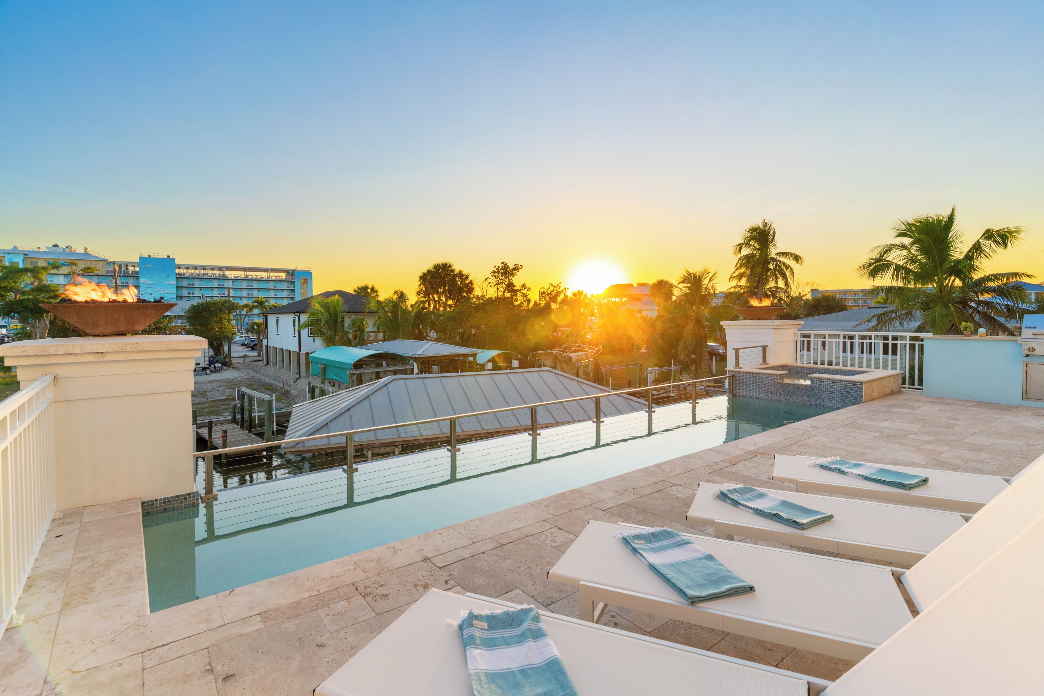 Un espace piscine aménagé sur le toit, avec des chaises longues et une vue sur le coucher du soleil.