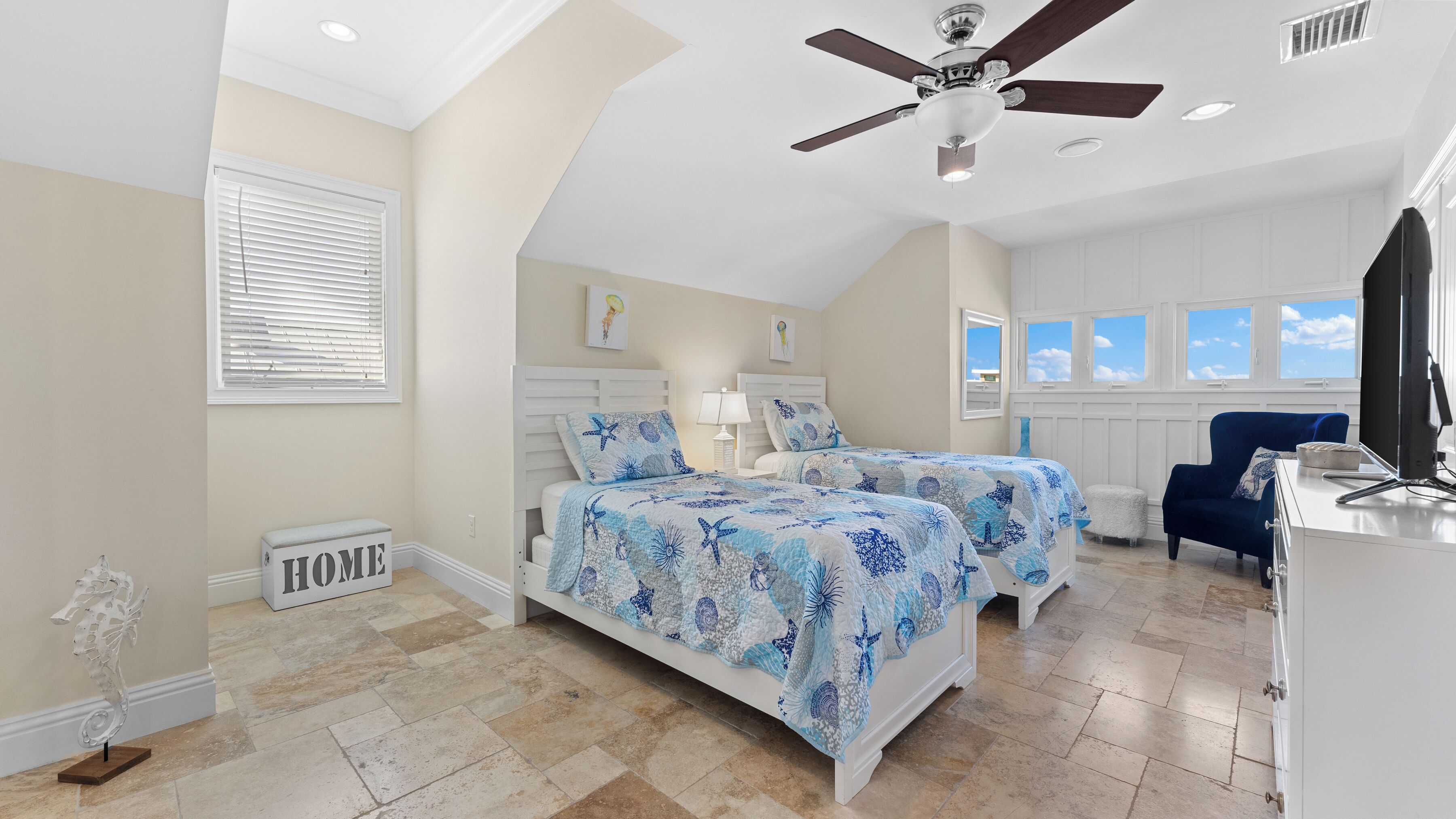 A bedroom with two beds, a ceiling fan, a desk, and a chair.