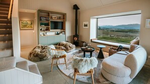 Una sala de estar acogedora con chimenea, un sofá, un sillón y una estantería.