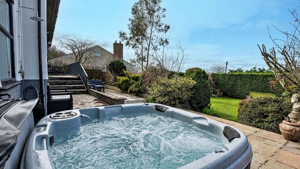A hot tub in a backyard with a house in the background. - Bungalow in Dyserth With Hot Tub & Waterfall (Rhyl)
