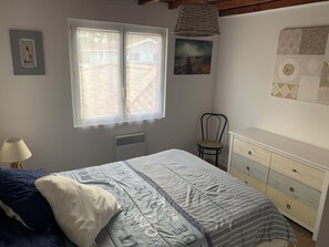 Ein Schlafzimmer mit Bett, Sessel, Schminktisch und Wandbildern.