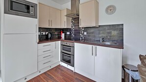 A kitchen with white cabinets, a microwave, a stove, and a sink. - Cottage on Kintyre Peninsula by Ellary Burn (Lochgilphead)