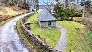 A stone cottage with a sloped roof, surrounded by a stone wall and a gravel path. - Cottage on Kintyre Peninsula by Ellary Burn (Lochgilphead)
