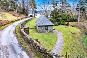 A stone cottage with a sloped roof, surrounded by a stone wall and a gravel path. - Cottage on Kintyre Peninsula by Ellary Burn (Lochgilphead)