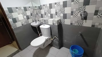 A bathroom with a toilet, sink, and a blue bucket.