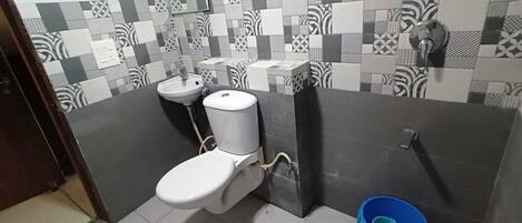 Une salle de bain avec des toilettes, un lavabo et un seau bleu.
