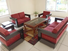 En moderne stue med røde sofaer, et sofabord i glas og et tæppe med mønster.