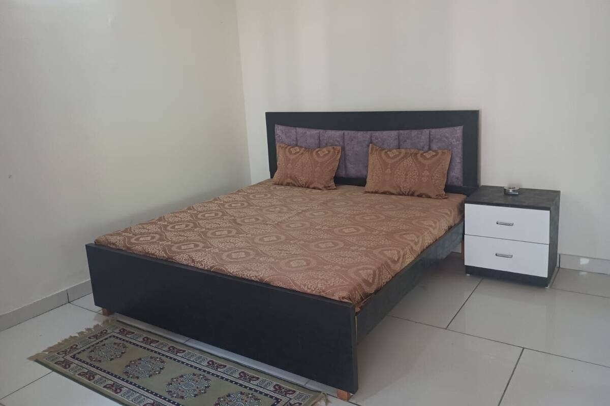 Une chambre à coucher avec un lit, une table de chevet et un tapis décoratif.