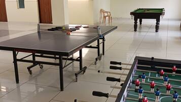 Un amplio espacio interior con mesa de futbolín, mesa de ping pong y mesa de billar.