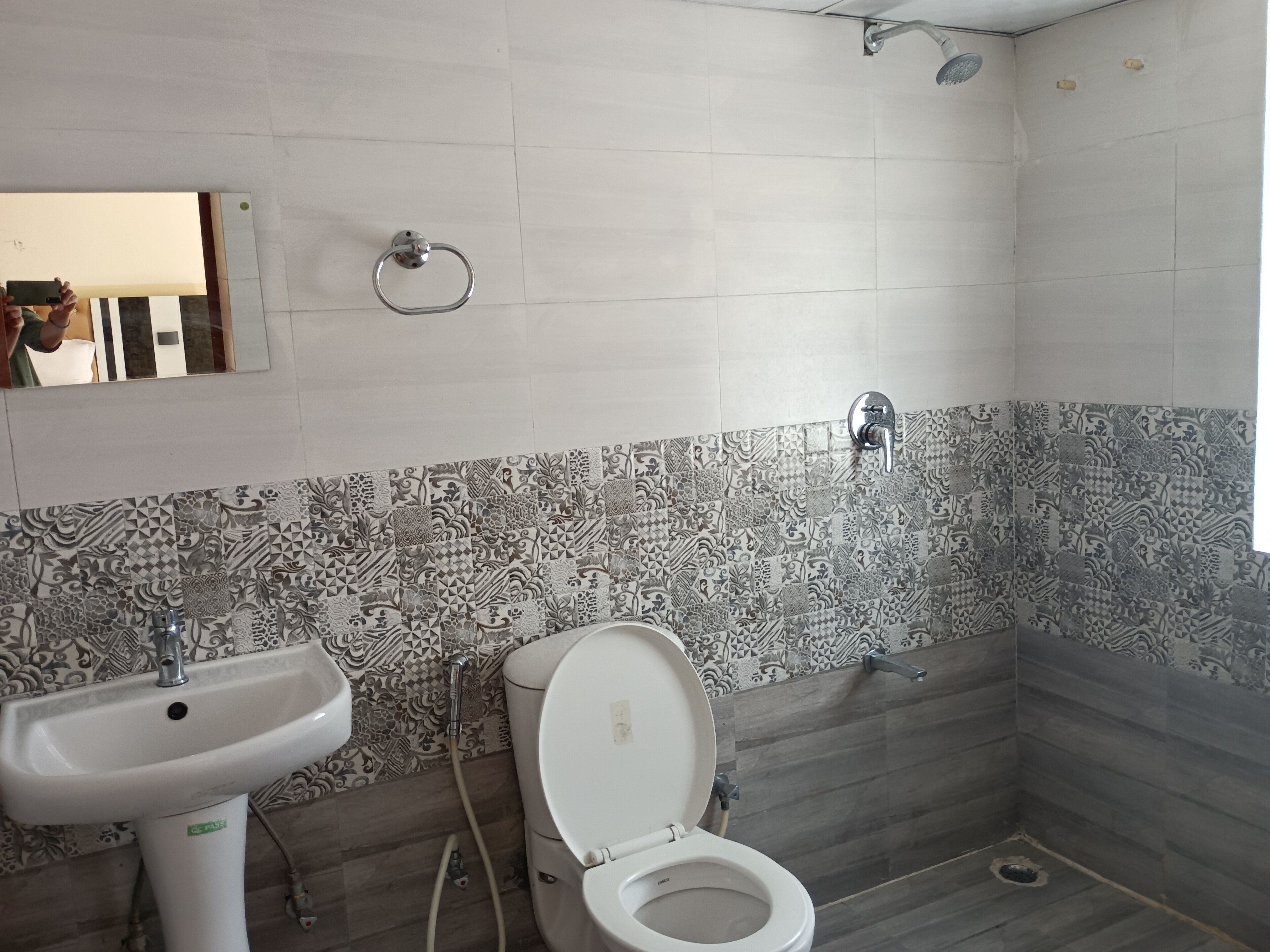 A bathroom with patterned tiles, a sink, toilet, and a shower.