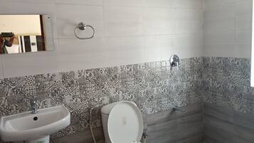 Une salle de bain avec des carreaux décorés, un lavabo, des toilettes et une douche.