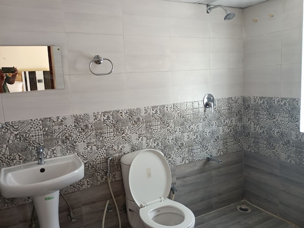A bathroom with patterned tiles, a sink, toilet, and a shower. - Hotel Katapathar Resort and Restaurant (Vikasnagar)