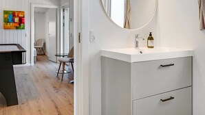 A modern bathroom with a white vanity, a round mirror, and a bottle of liquid soap.