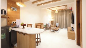 A modern kitchen with a central island, wooden ceiling beams, and a dining area with a table and chairs.