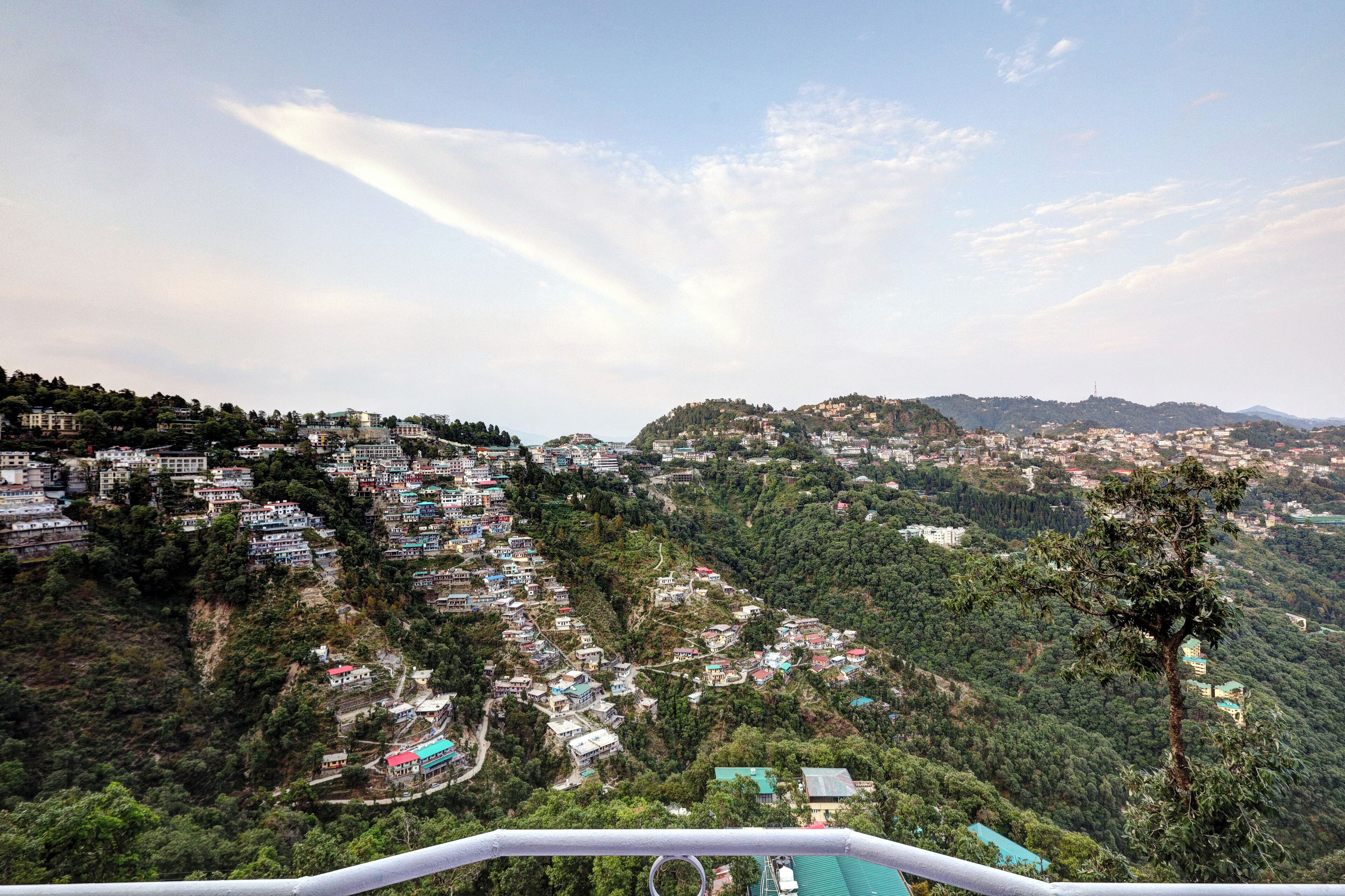 A panoramic view of a hillside town with buildings nestled among trees.