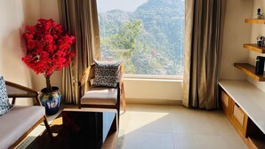 A modern living room with a large window, a sofa, a coffee table, and a vase of red flowers.