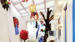 A narrow hallway with a stone floor, blue railings, and hanging floral decorations.