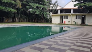 A swimming pool with a tiled deck, surrounded by trees and a building labeled "SPA".